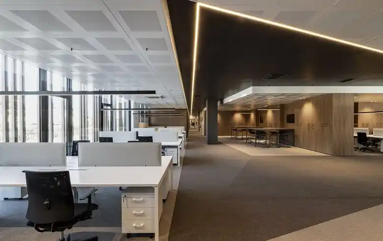 Modern open-plan office with desks and ambient ceiling lighting